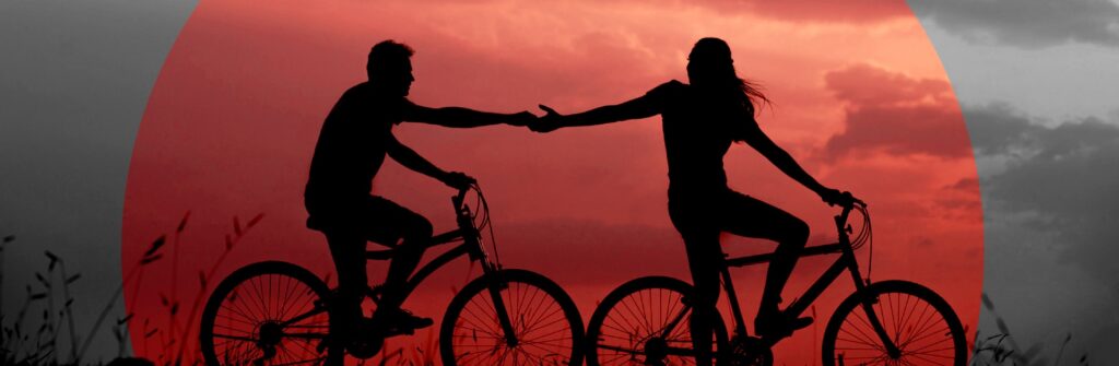 Couple on bicycles reaching out.